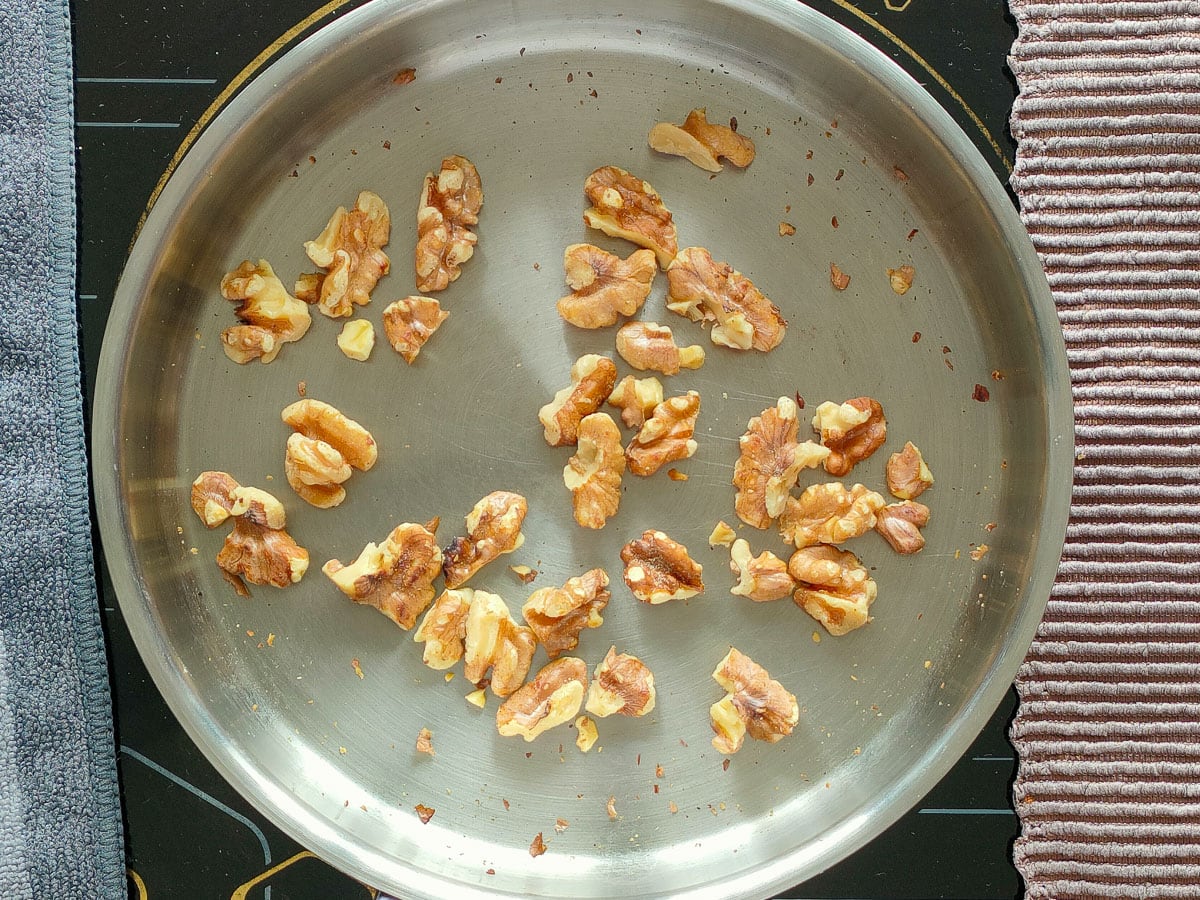 Toasted walnuts in a small pan.