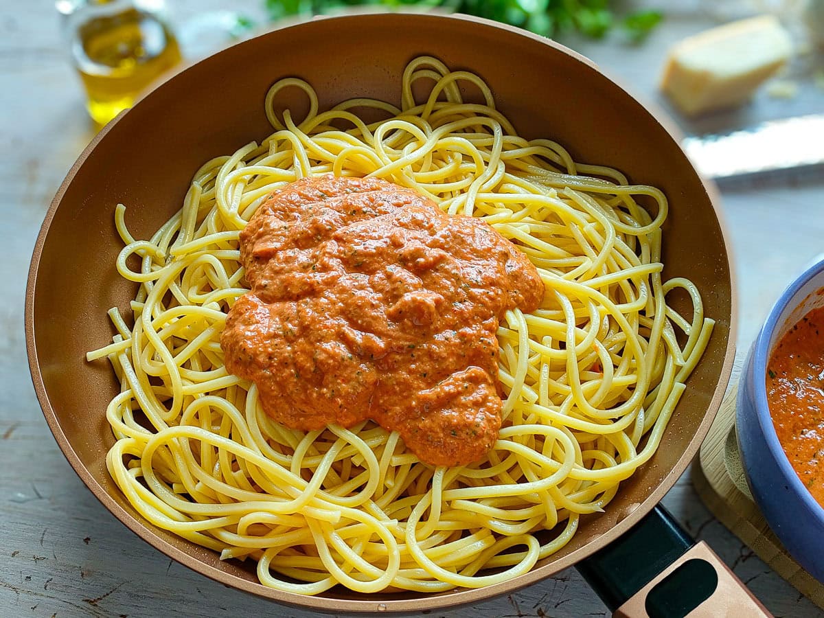 Bell pepper pesto on pasta in a pan.