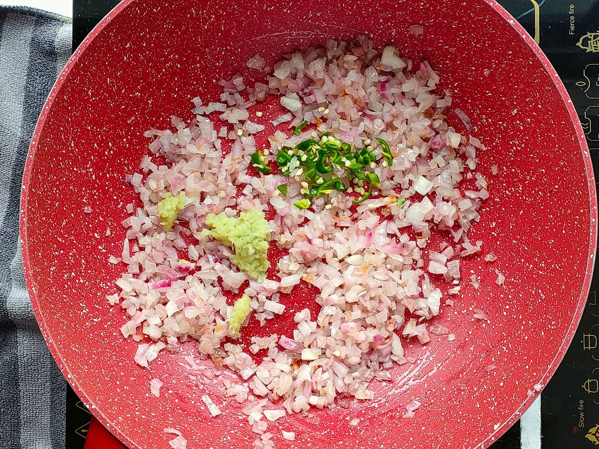 Chillies and ginger-garlic paste with sauteed onions in a deep pan.