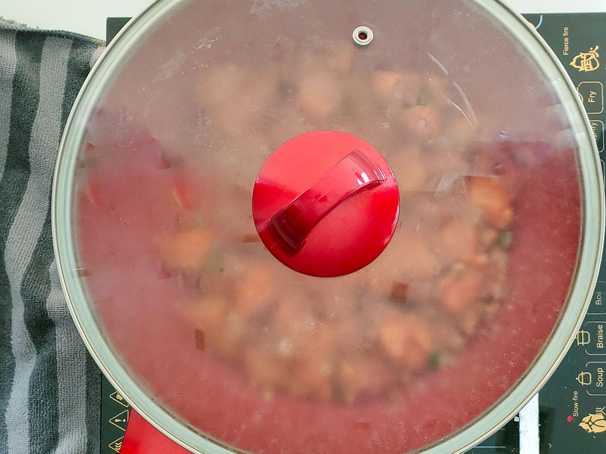 Curry leaf chicken cooking in a covered deep pan.