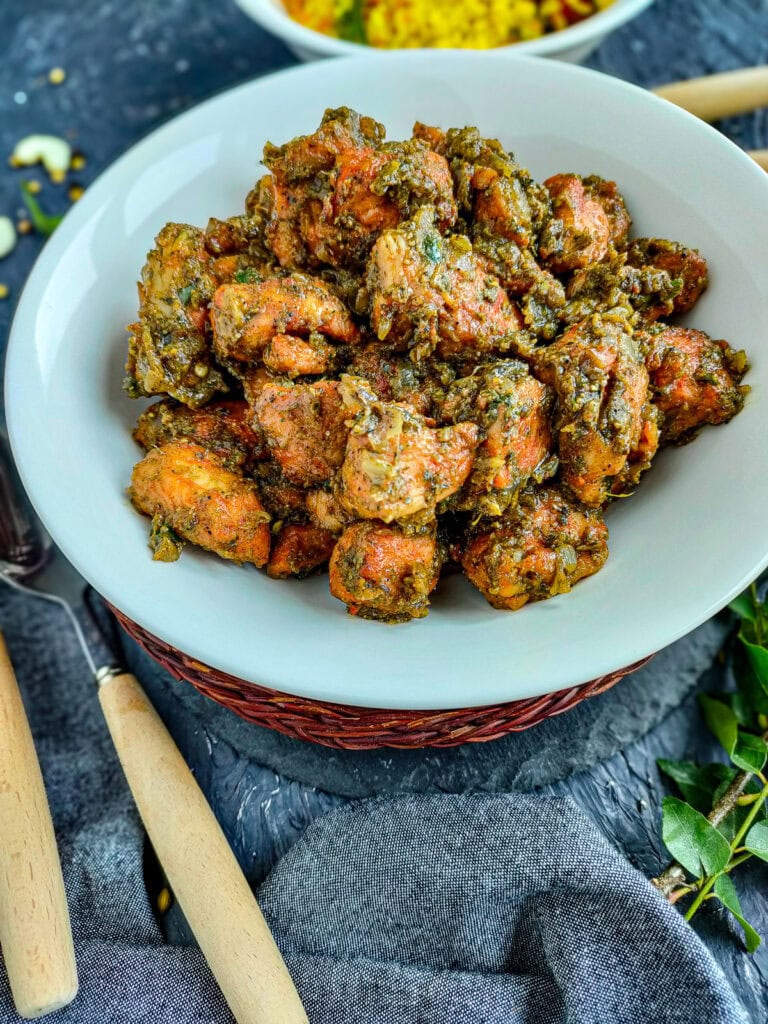 Curry leaf chicken on a white plate.