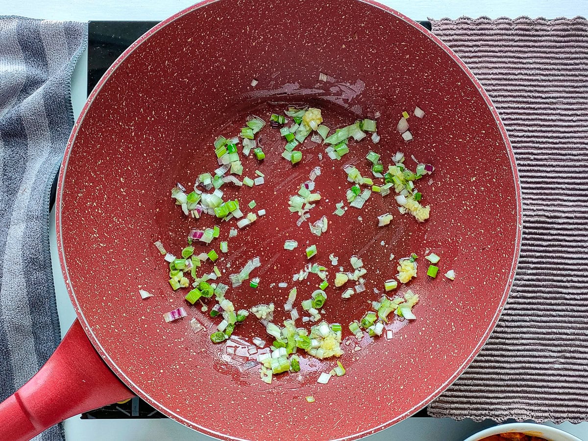 Onions and garlic being sauteed in a pan.