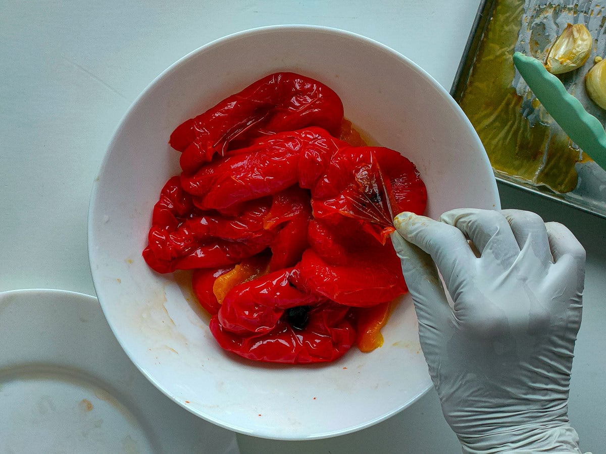 Peeling roasted peppers in a white bowl.