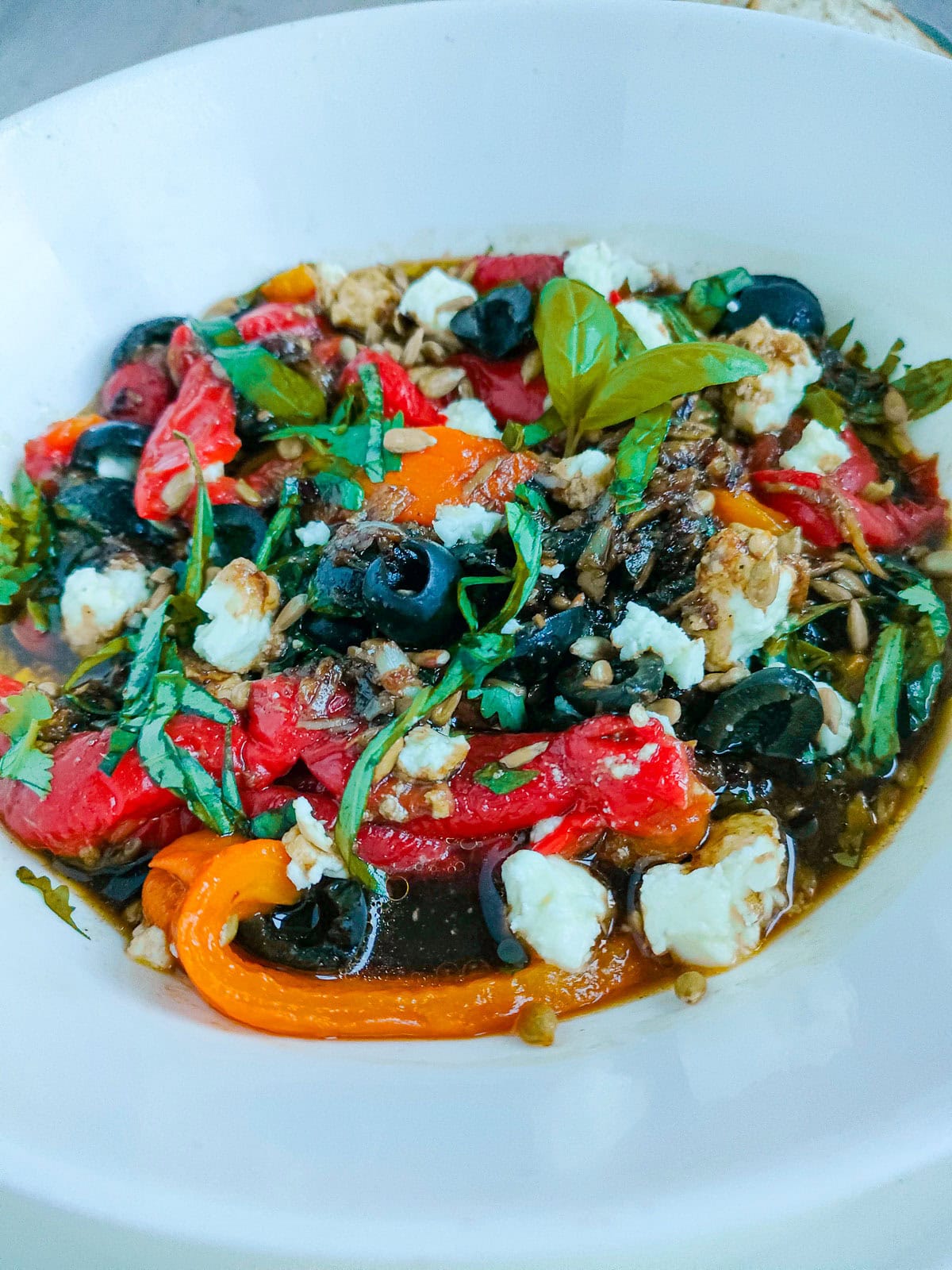 Salad with roasted peppers in a white bowl.