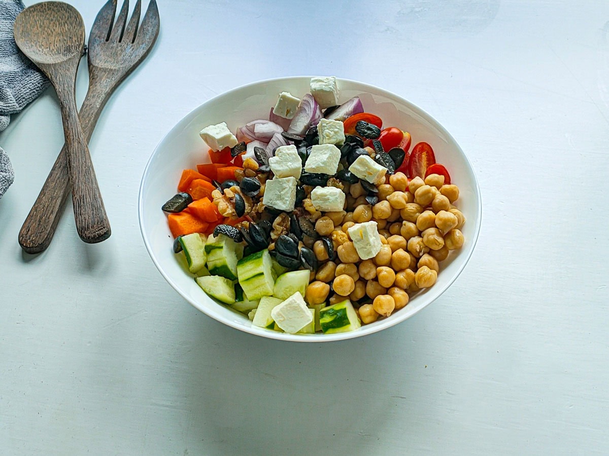 Vegetables, chickpeas and feta in a white bowl.