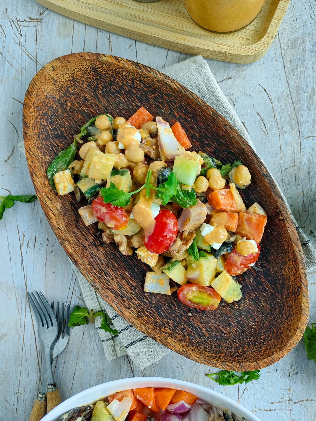 Easy hummus salad with fresh veggies on a wooden platter.