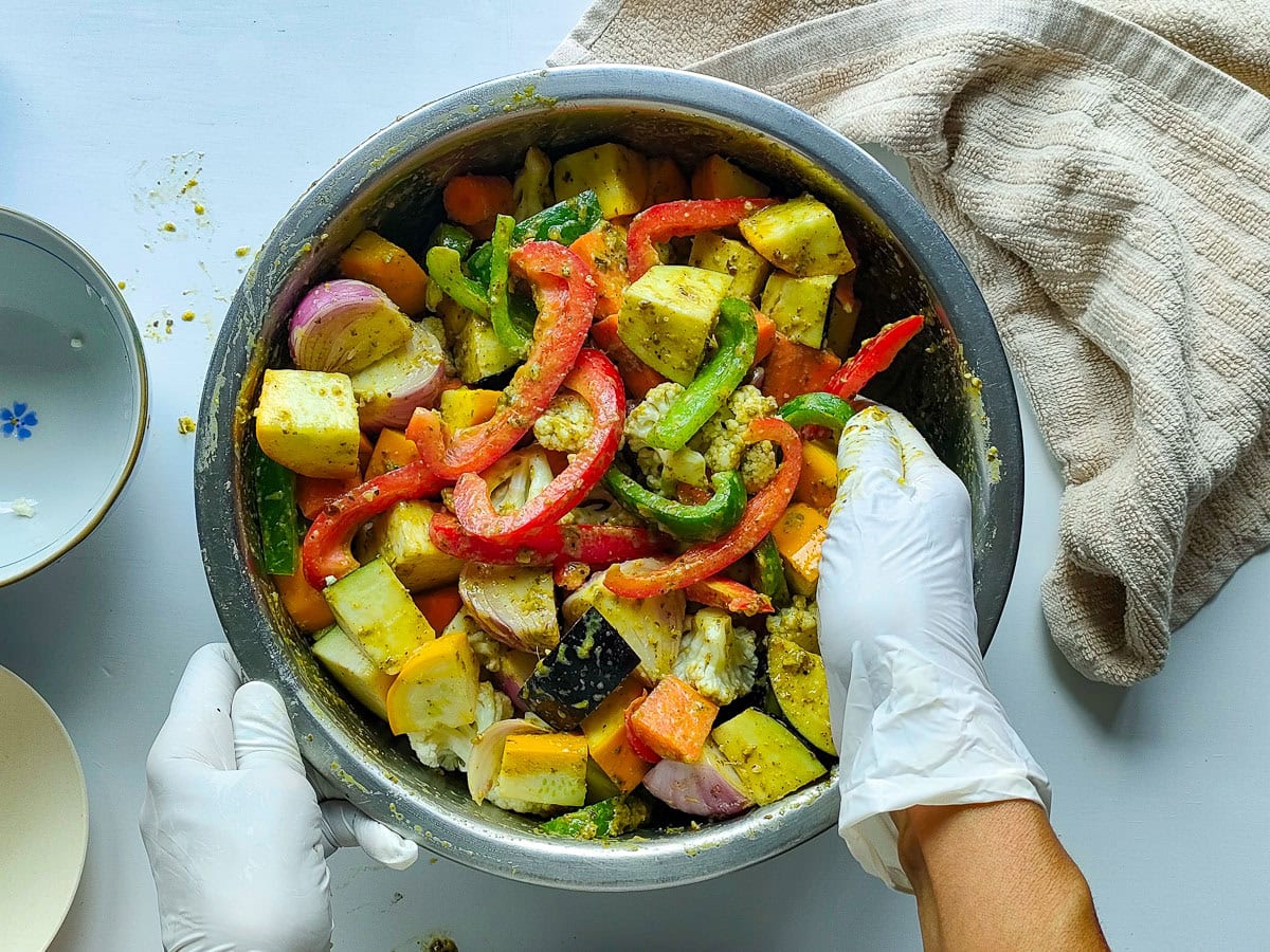 Easy Roasted Pesto Vegetables (Mediterranean style) Diced vegetables being tossed with pesto seasoning.