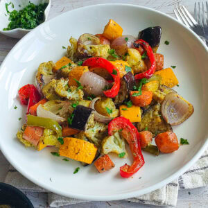 Easy Roasted Pesto Vegetables (Mediterranean style) Roasted vegetables with basil pesto on a white plate.