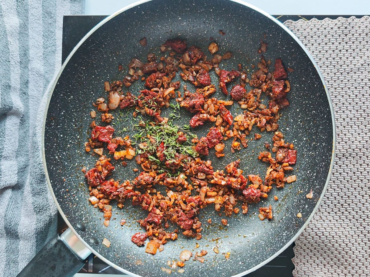 Cajun Pasta with Salmon (without cream) Onion tomato mixture with fresh thyme in a pan.