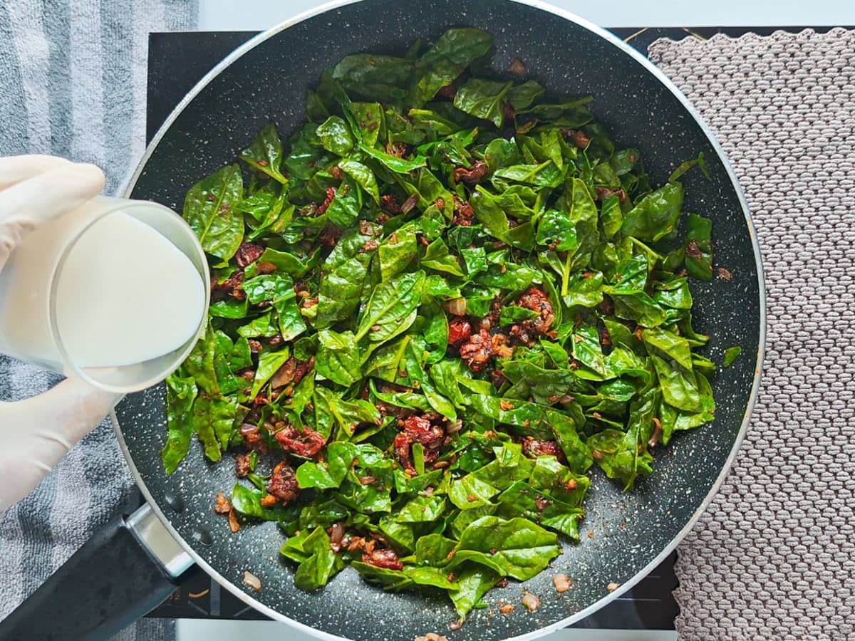 Cajun Pasta with Salmon (without cream) Milk beig added to tomato spinach mixture in a pan.