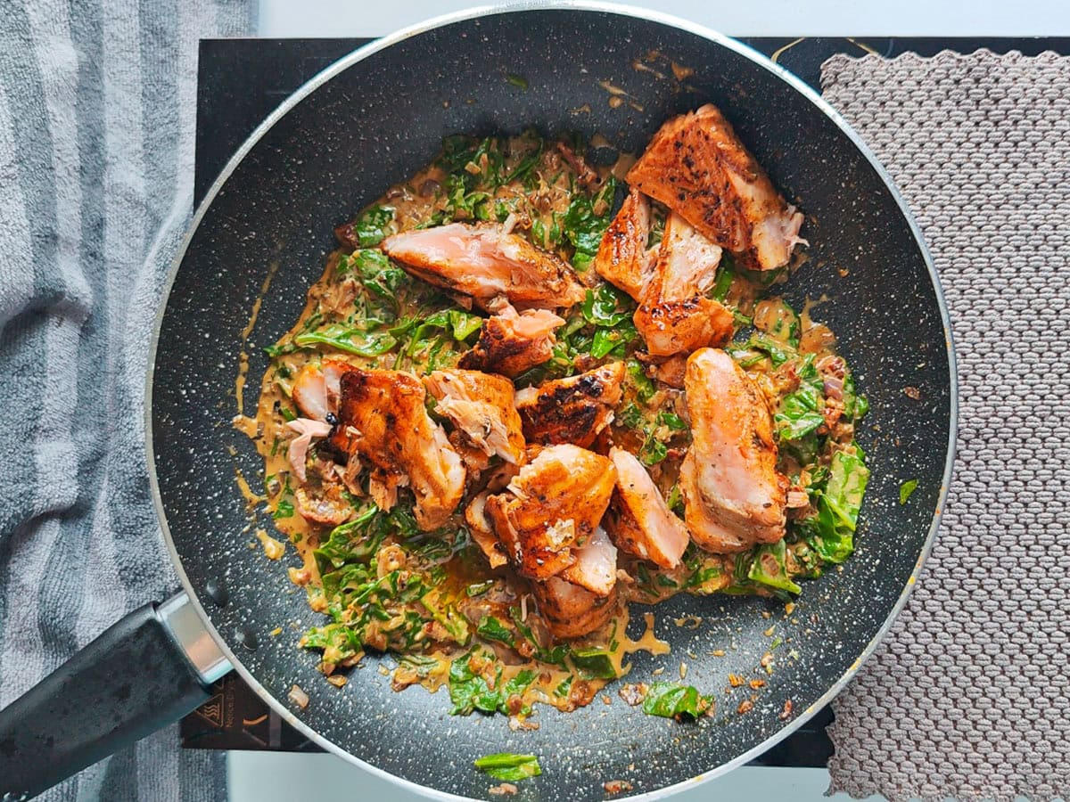 Cajun Pasta with Salmon (without cream) Flaky Cajun salmon on creamy sauce in a large pan.
