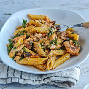 Cajun Pasta with Salmon (without cream) Cajun salmon pasta on a white plate with a fork in it.