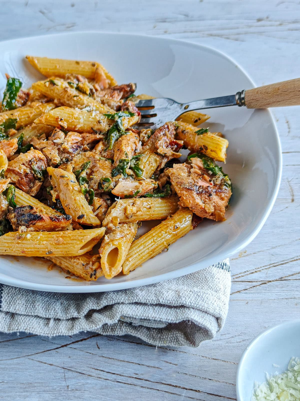 Cajun Pasta with Salmon (without cream) Salmon pasta without cream on a white plate with a fork in it.