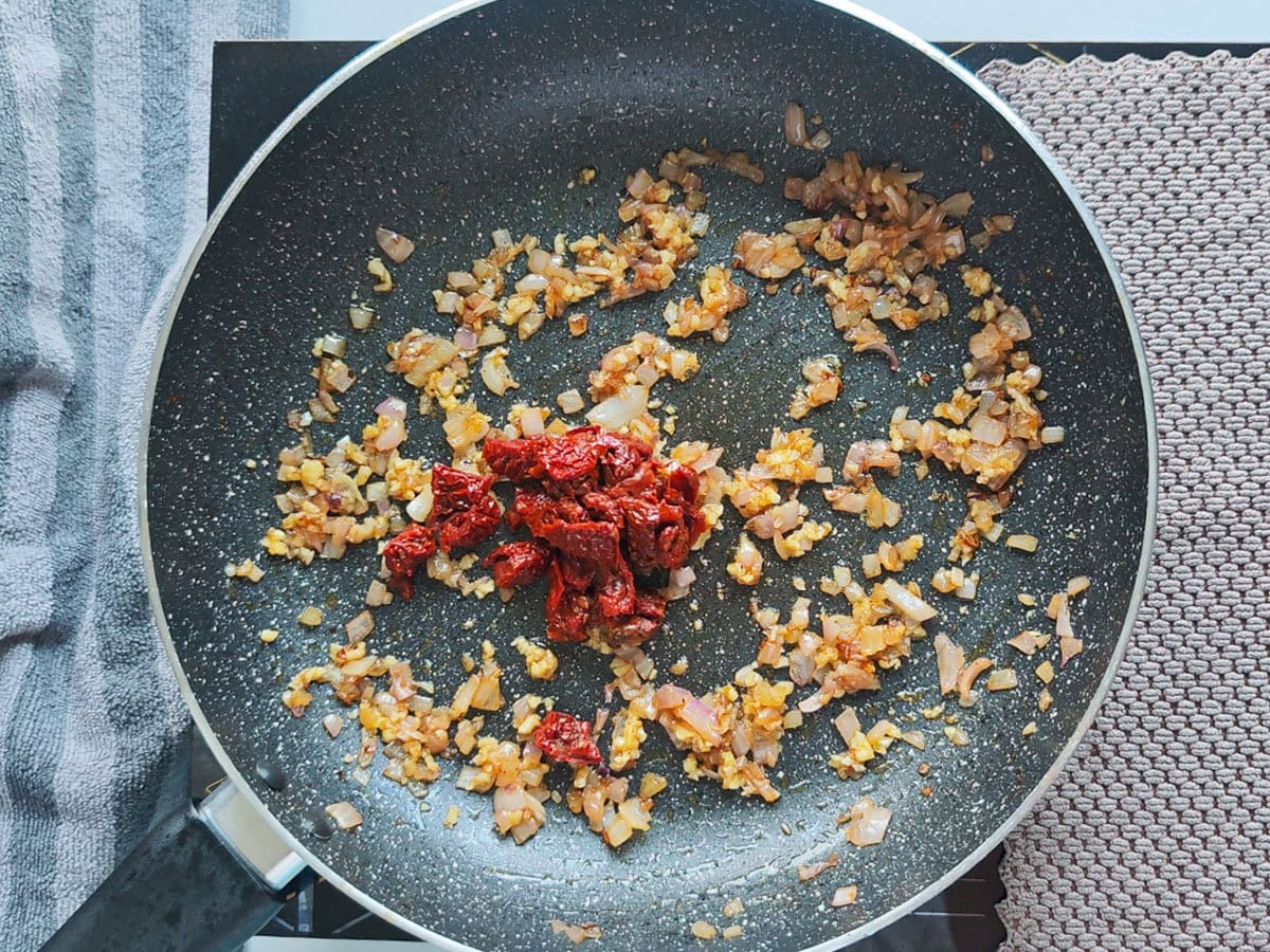 Cajun Pasta with Salmon (without cream) Sun dried tomatoes with sauteed onions in a pan.