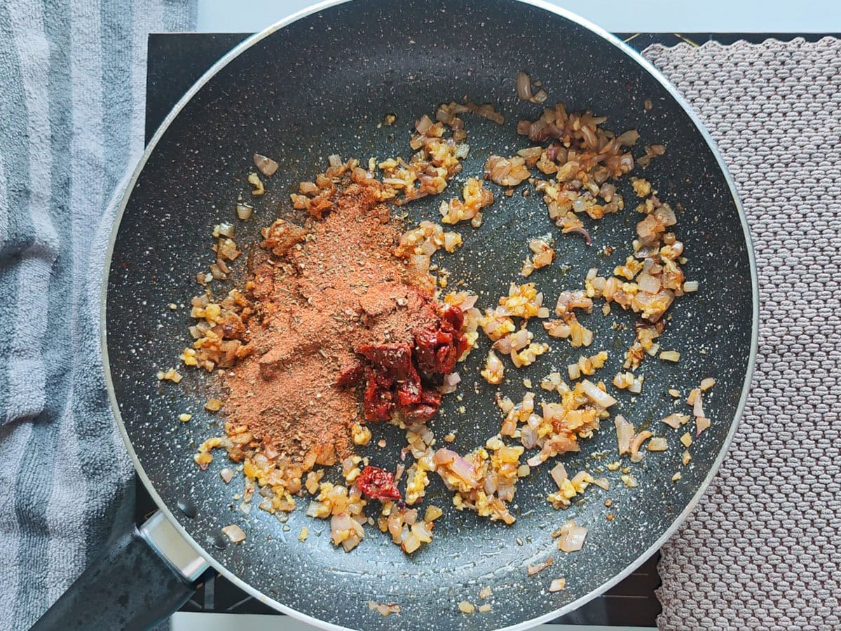 Cajun Pasta with Salmon (without cream) Onion tomato mixture with Cajun spices in a pan.
