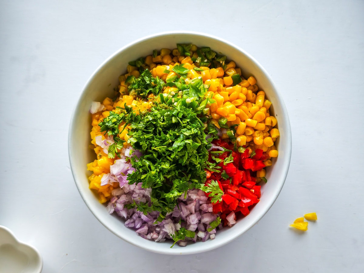 Easy Corn Mango Salsa Ingredients for mango corn salsa recipe in a white bowl.