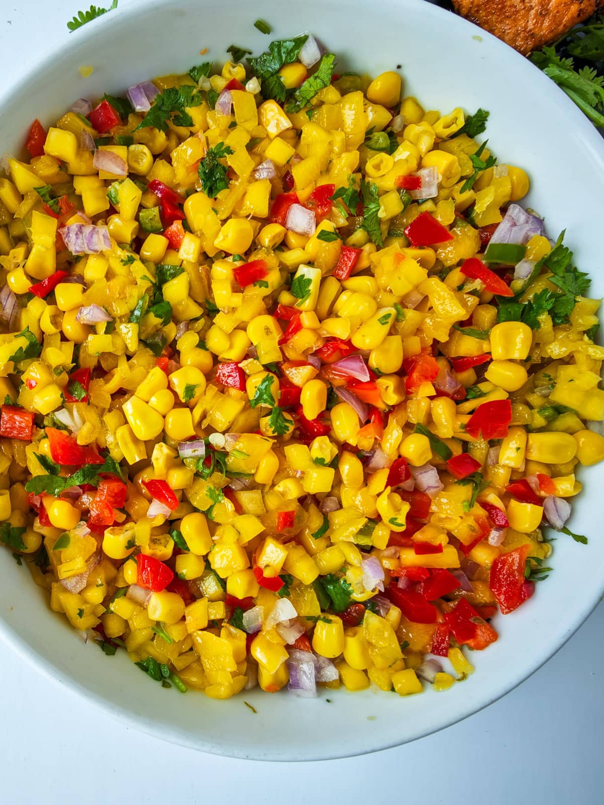 Easy Corn Mango Salsa Mango salsa with corn in a white bowl.
