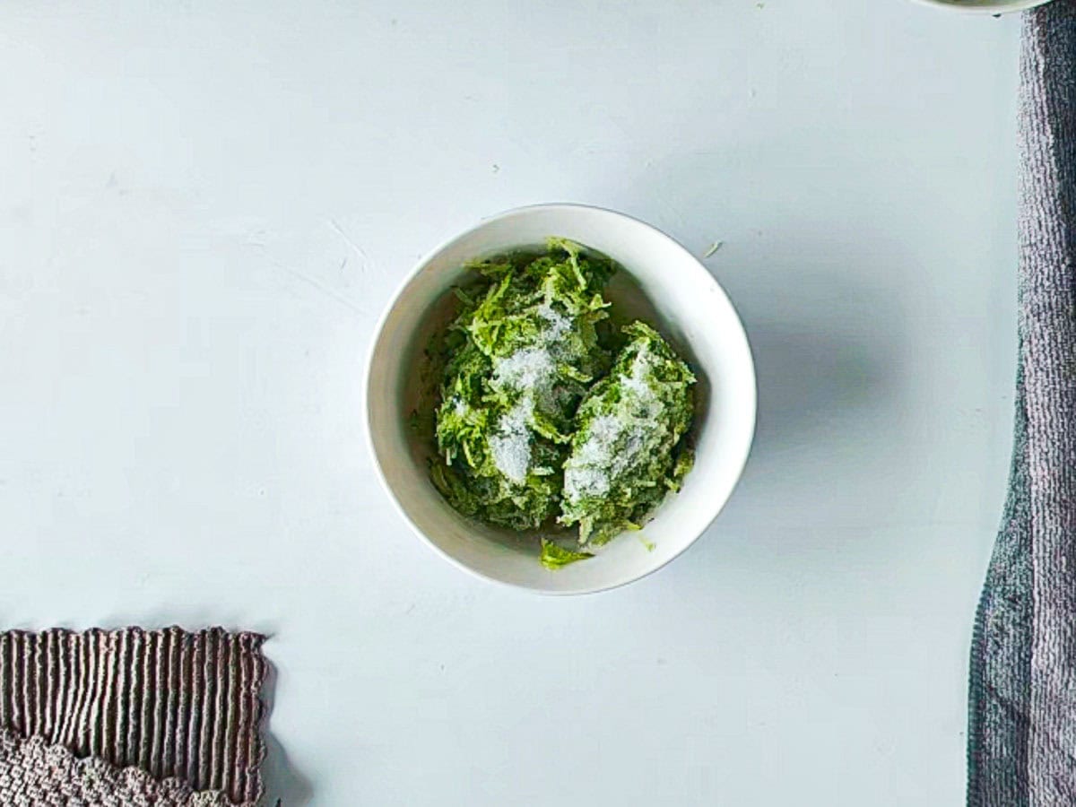 Creamy Cucumber Dill Tzatziki (Greek Yogurt Cucumber Dip) Grated cucumber with salt in a bowl.