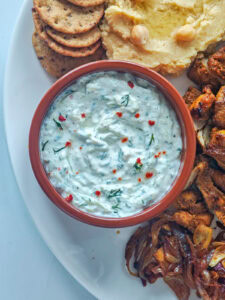 Creamy Cucumber Dill Tzatziki (Greek Yogurt Cucumber Dip) Creamy tzatziki in a brown bowl on a chicken shawarma plate.