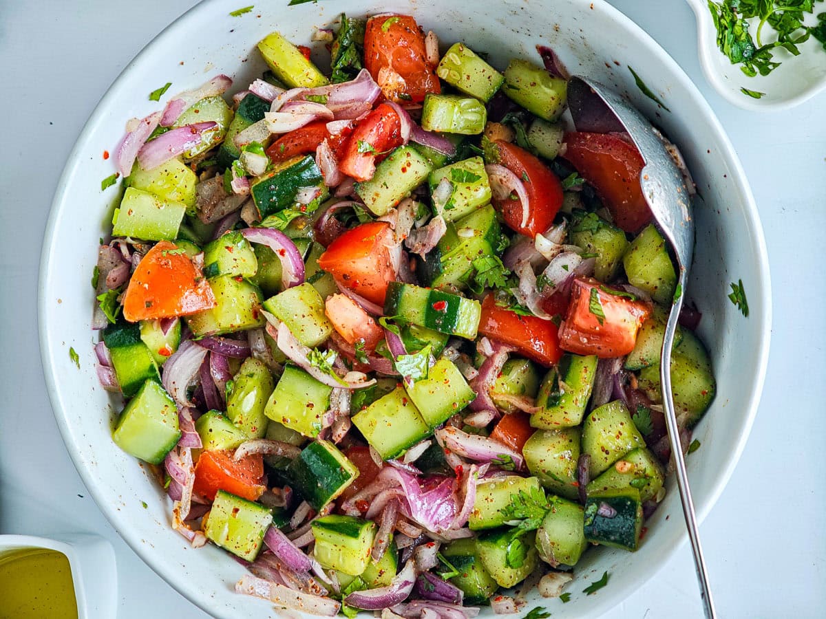Quick Cucumber Tomato Mediterranean Salad (no dressing required) Mediterranean diet salad in a white bowl.