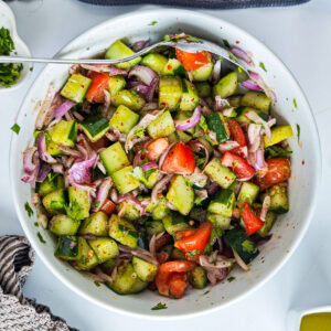 Quick Cucumber Tomato Mediterranean Salad (no dressing required) Mediterranean tomato cucumber salad in a white bowl.