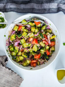 Quick Cucumber Tomato Mediterranean Salad (no dressing required) Cucumber tomato Mediterranean salad in a white bowl.