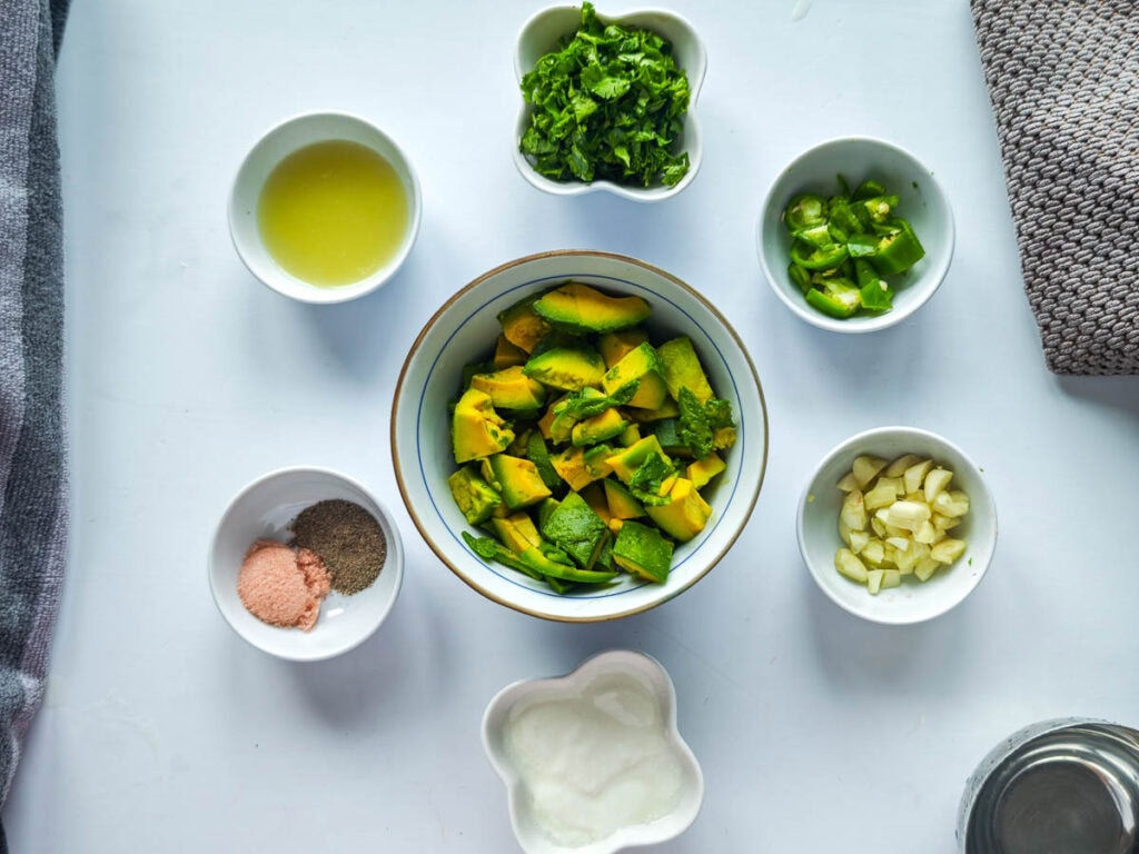 Prepared ingredients for avocado cream sauce in separate bowls.