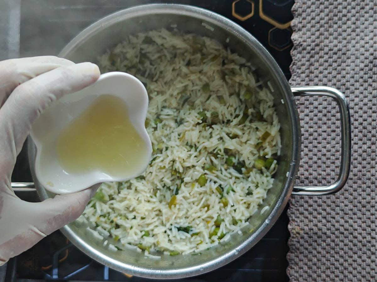 Easy One Pot Cilantro Lime Basmati Rice Lime juic being added from a small bowl to cooked basmati rice in a large pot.