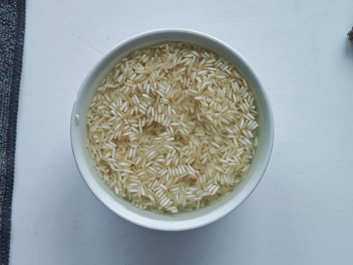 Easy One Pot Cilantro Lime Basmati Rice Basmati rice soaked in water in a white bowl.