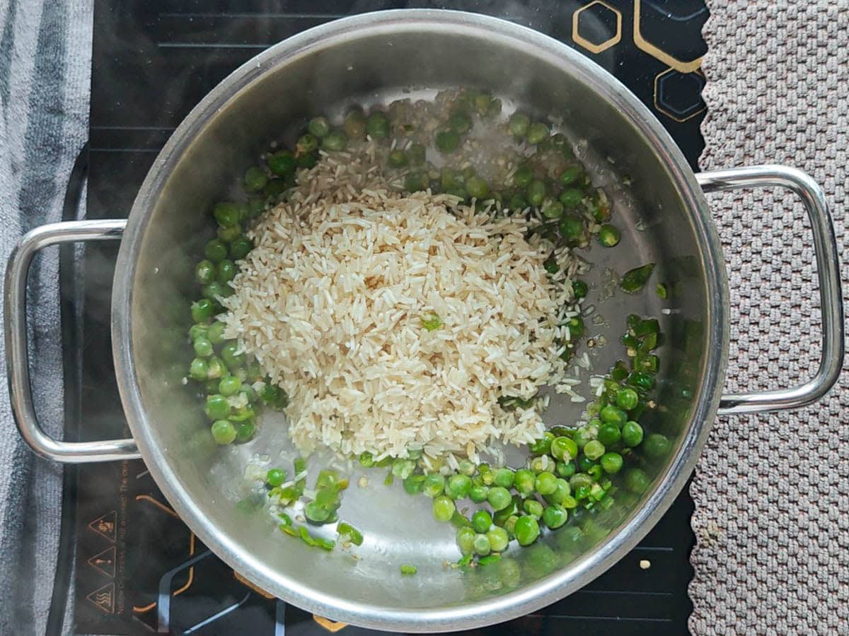 Easy One Pot Cilantro Lime Basmati Rice Soaked Basmati rice with green peas, jalapenos and garlic in a pot.