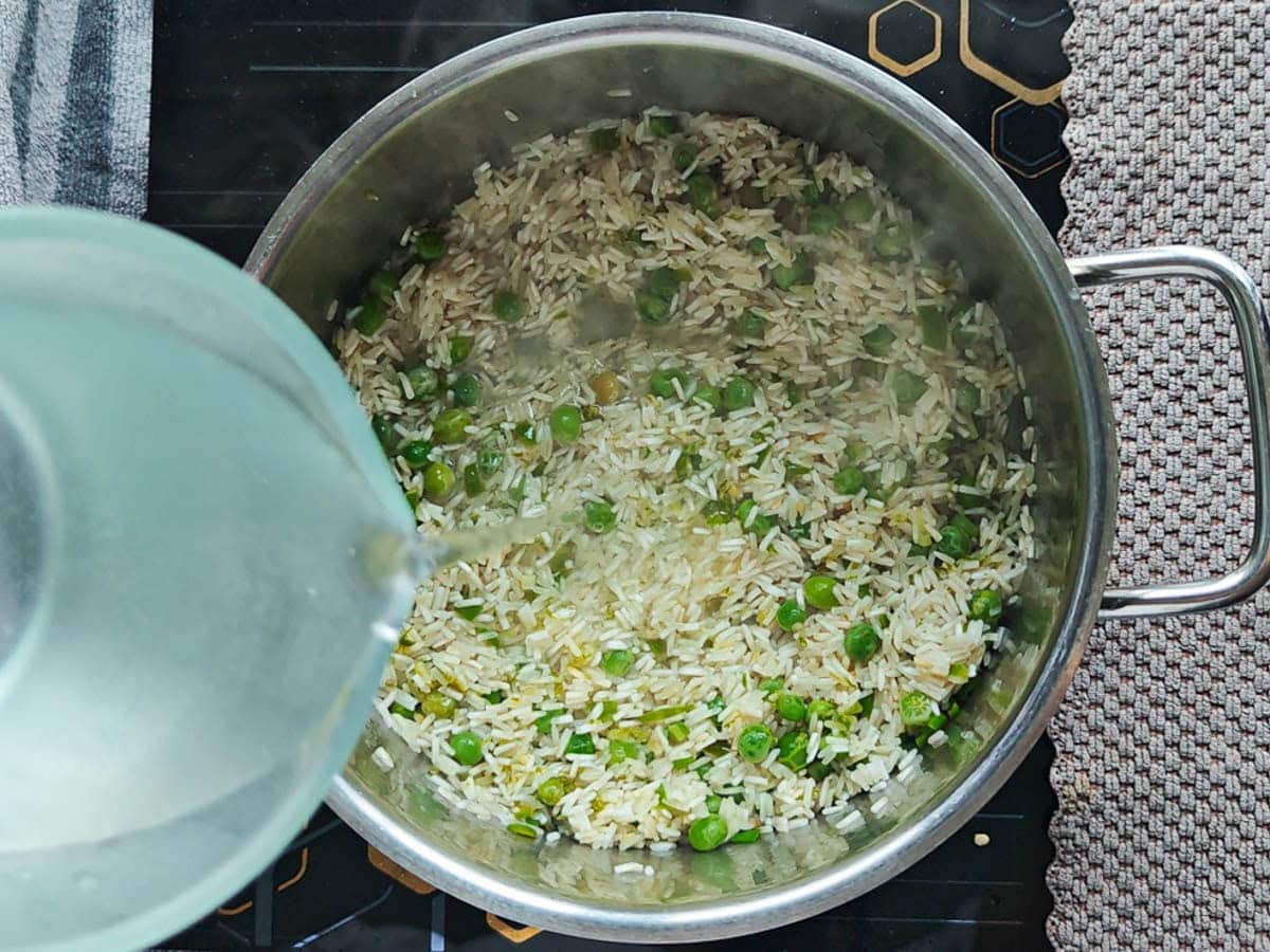 Easy One Pot Cilantro Lime Basmati Rice Water being added to rice and other ingredients in a pot.