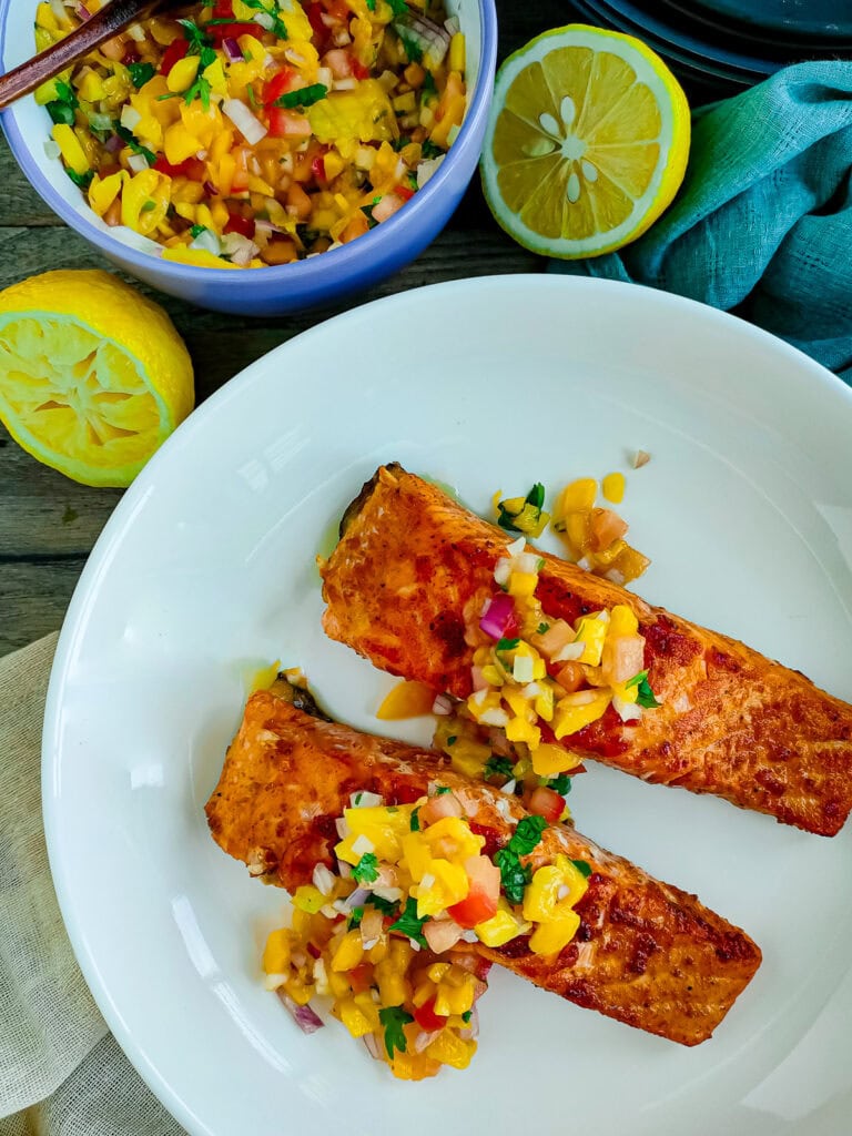 Jalapeno mango salsa with paprika salmon on a white plate.