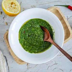 Low-calorie Basil Chimichurri (without excess oil) Chimichurri with basil in a deep plate with a spoon in it.