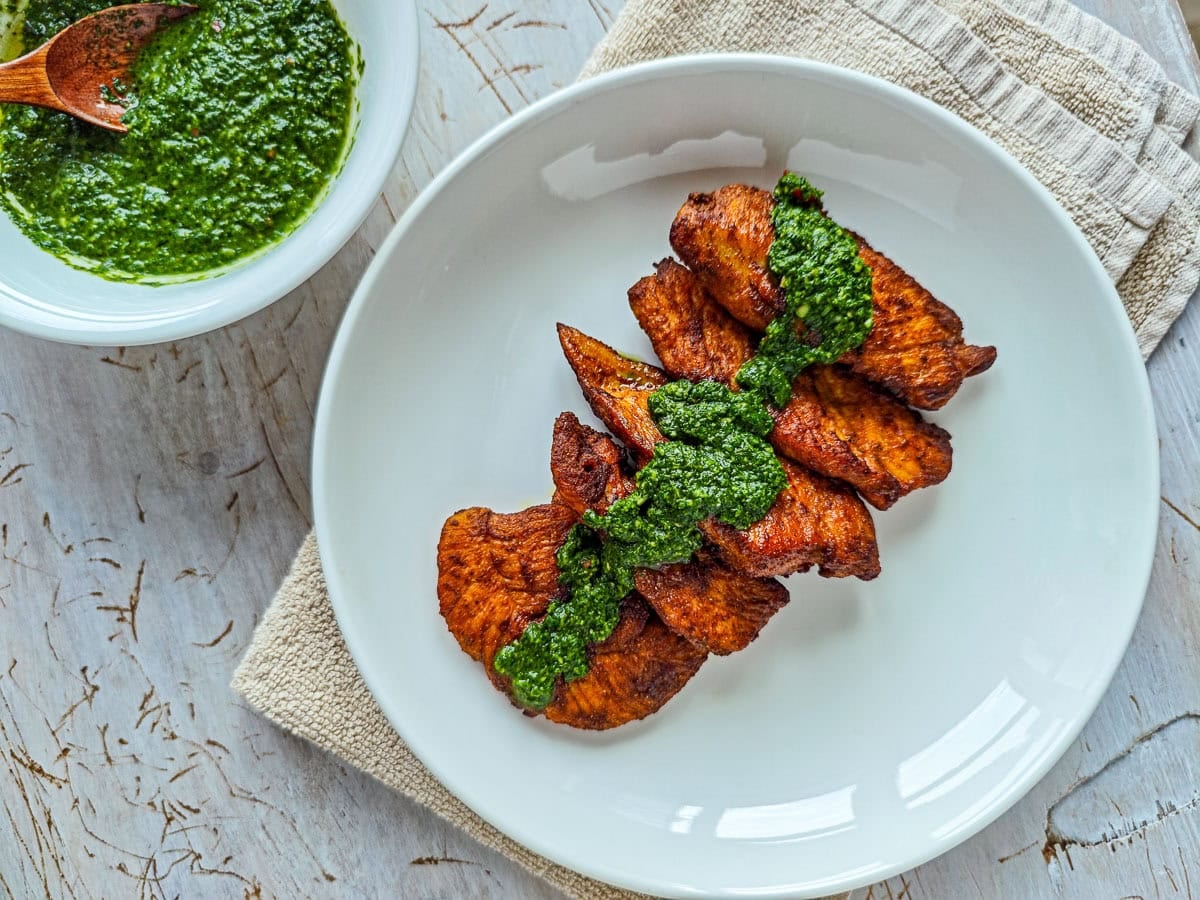 Low-calorie Basil Chimichurri (without excess oil) Chimichurri with basil and parsley drizzled on roasted chicken breast on a plate.