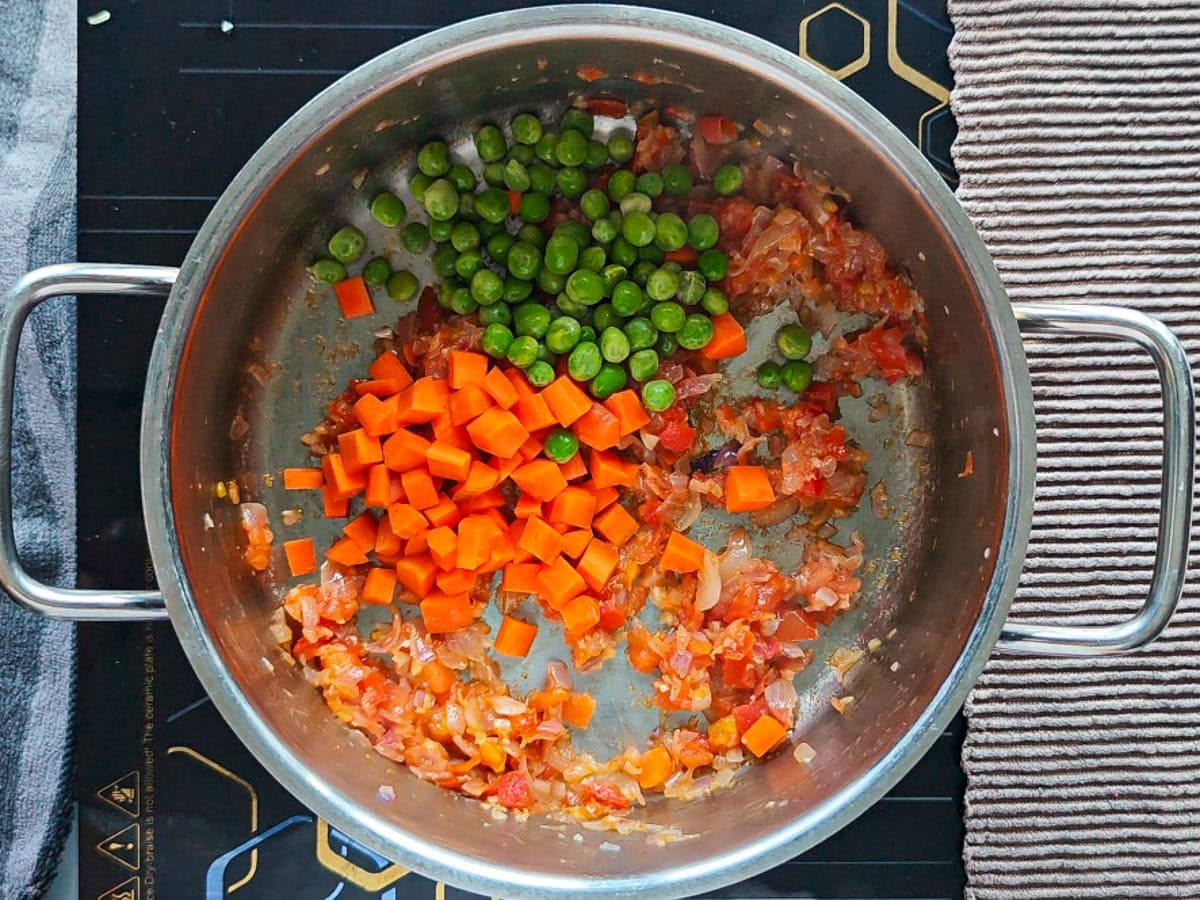 Easy Chimichurri Rice with Vegetables Carrots and peas with sauteed onion and tomatoes in a pot.