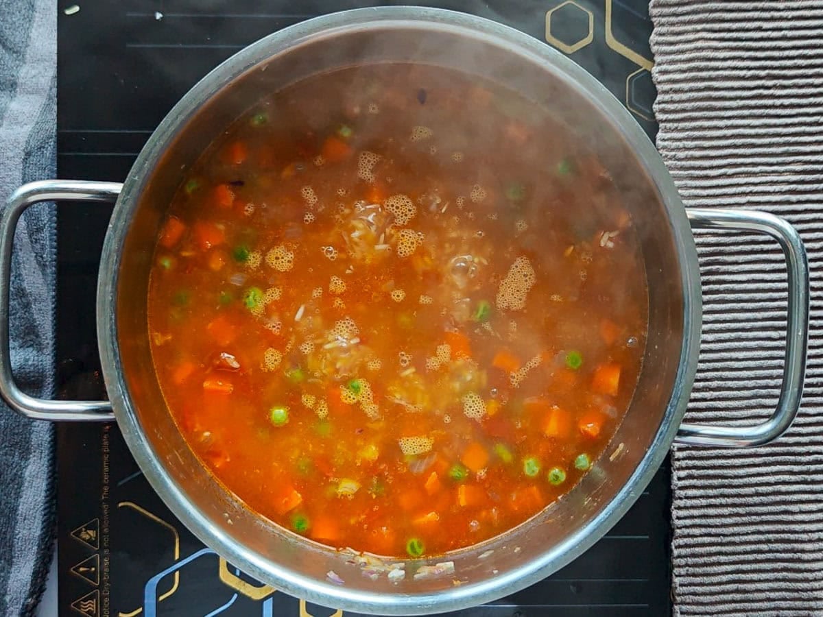 Easy Chimichurri Rice with Vegetables Rice with vegetables and water simmering in a pot.