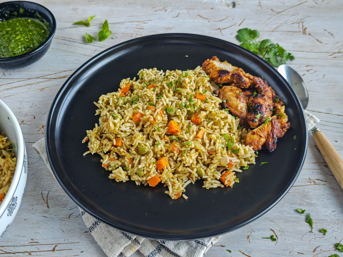 Easy Chimichurri Rice with Vegetables Chimichurri rice served with pan-fried chicken on a black plate.