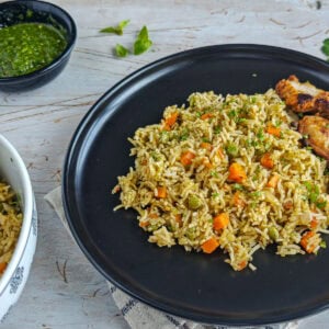 Easy Chimichurri Rice with Vegetables Chimichurri rice served with pan-fried chicken on a black plate.