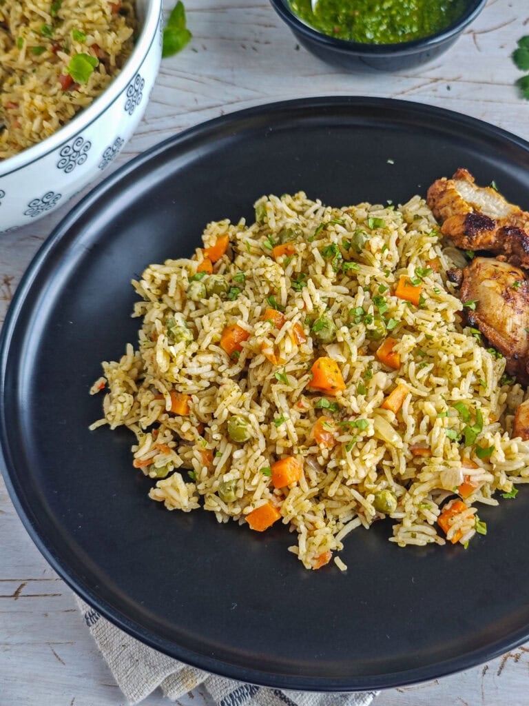 Basil chimichurri rice served with chicken on a black plate.