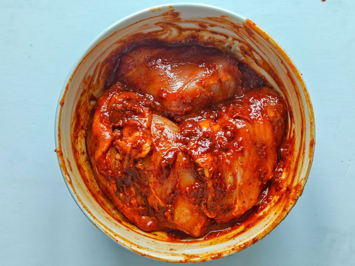 Easy Gochujang Chicken Thighs (Sticky & Oven-Baked) Chicken thighs marinated in gochujang marinade in a large bowl.