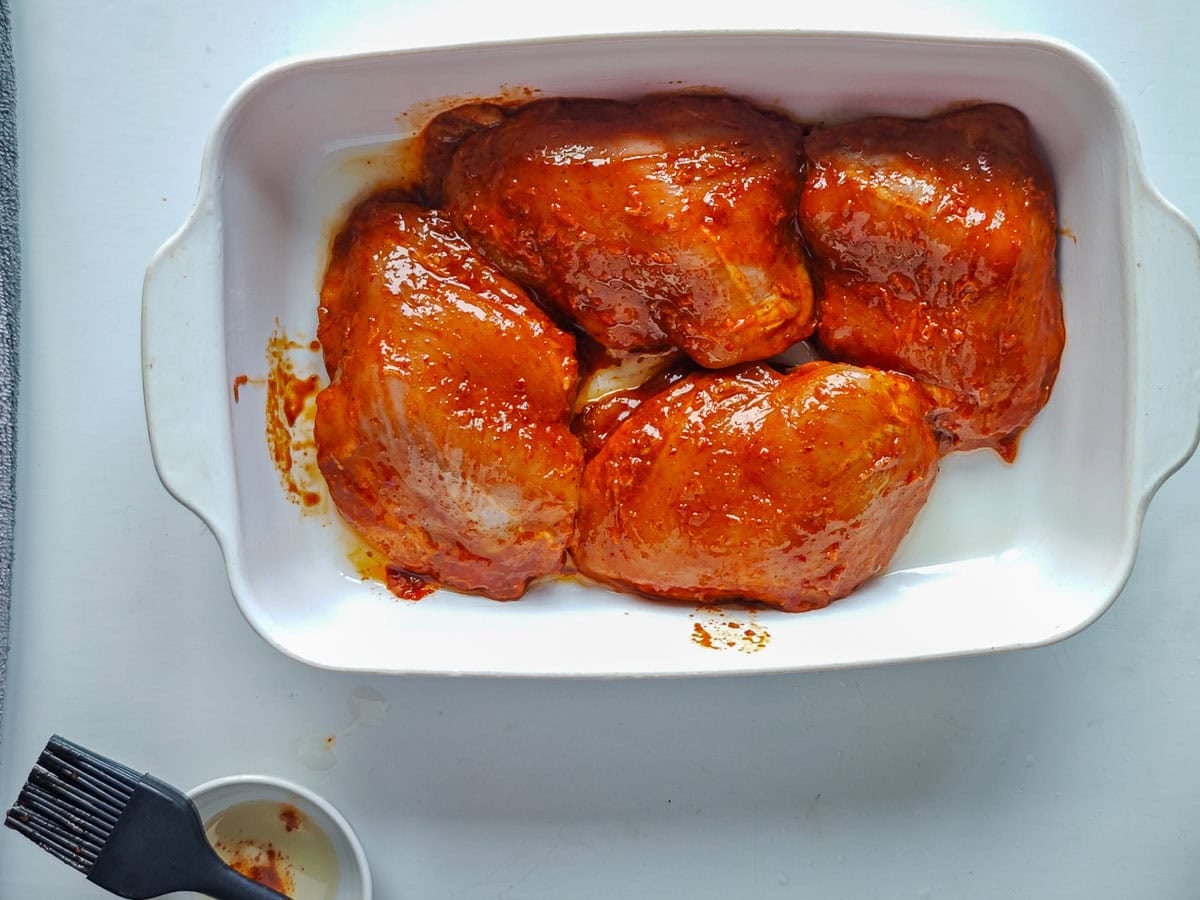 Easy Gochujang Chicken Thighs (Sticky & Oven-Baked) Gochujang marinated chicken in a baking dish brushed with oil.