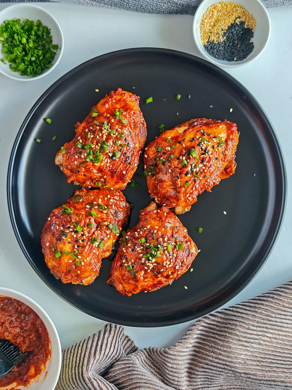 Easy Gochujang Chicken Thighs (Sticky & Oven-Baked) Baked gochujang chicken thighs on a black plate.