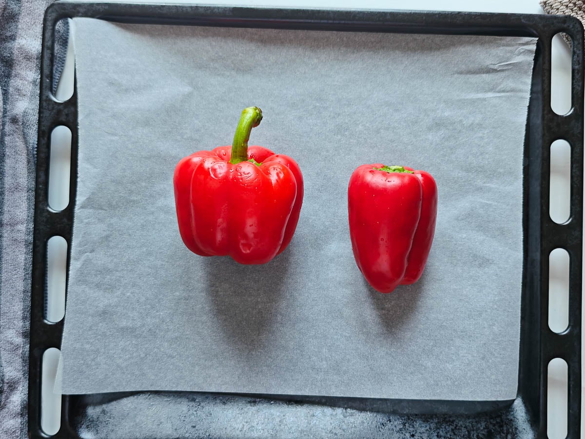 Easy Red Chimichurri Sauce with Roasted Peppers 2 red peppers on a sheet pan lined with parchment paper.