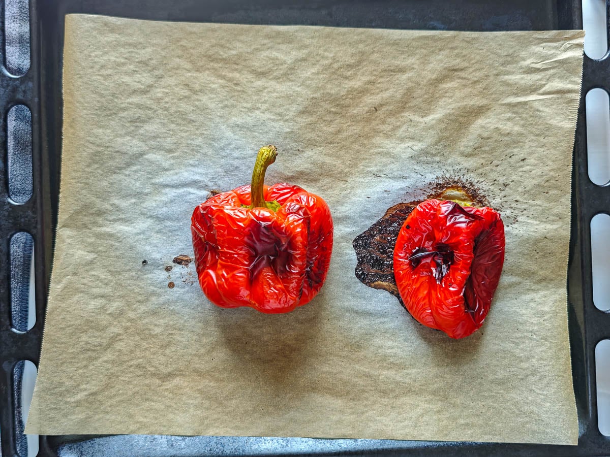 Easy Red Chimichurri Sauce with Roasted Peppers 2 roasted red peppers on a sheet pan lined with parchment paper.
