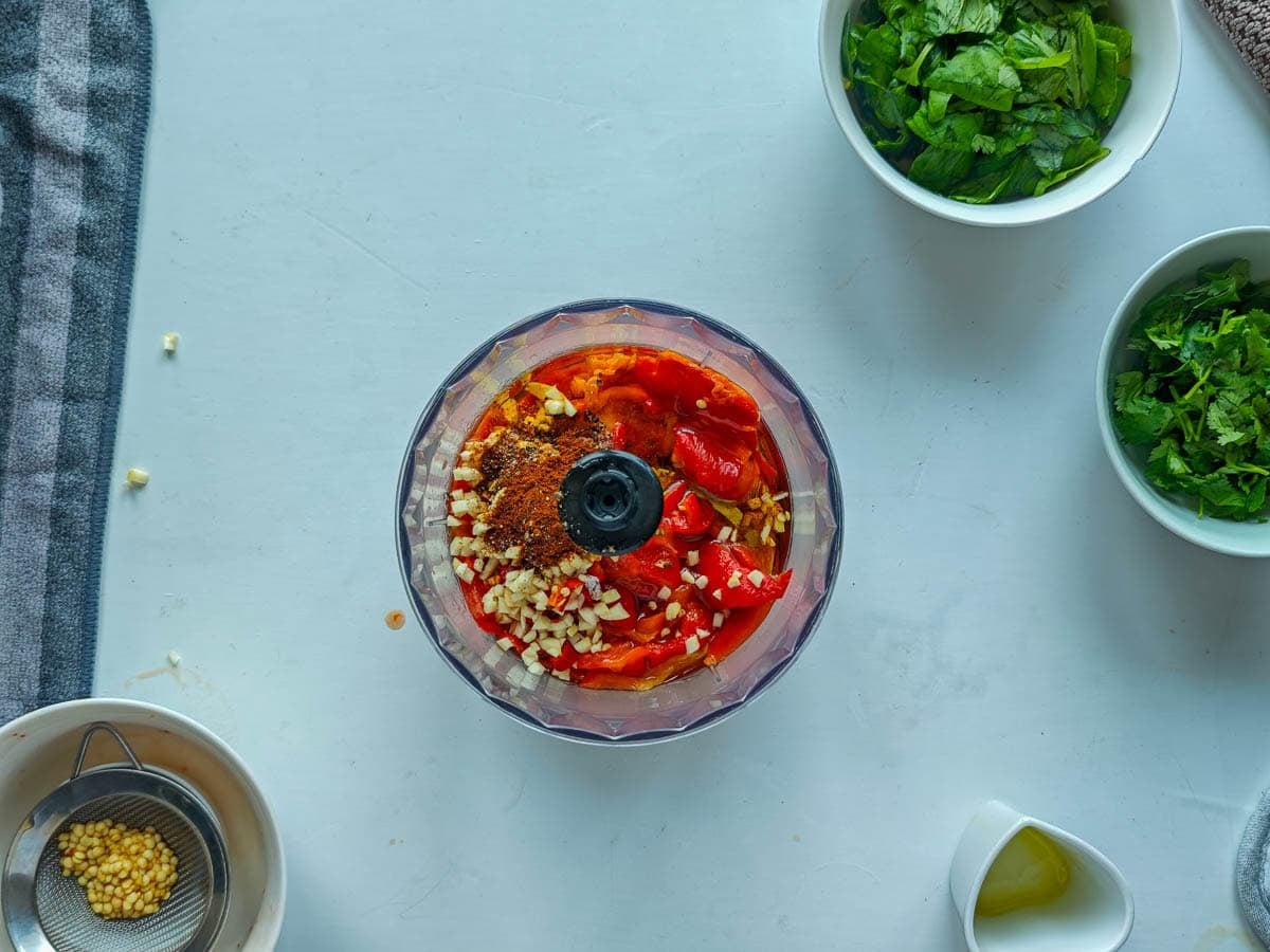 Easy Red Chimichurri Sauce with Roasted Peppers Ingredients for roasted red pepper chimichurri in an immersion blender.