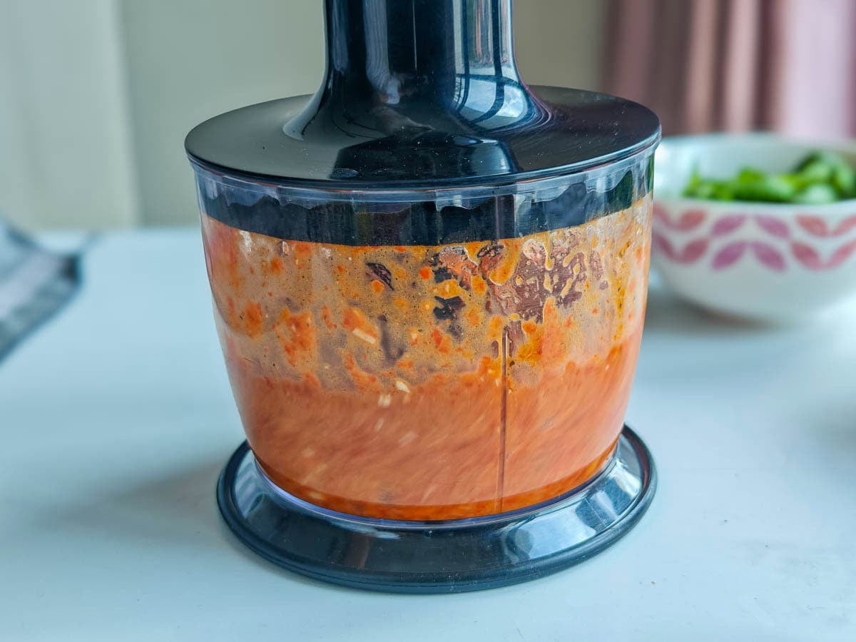 Easy Red Chimichurri Sauce with Roasted Peppers Roasted peppers being blended with spices in an immersion blender.