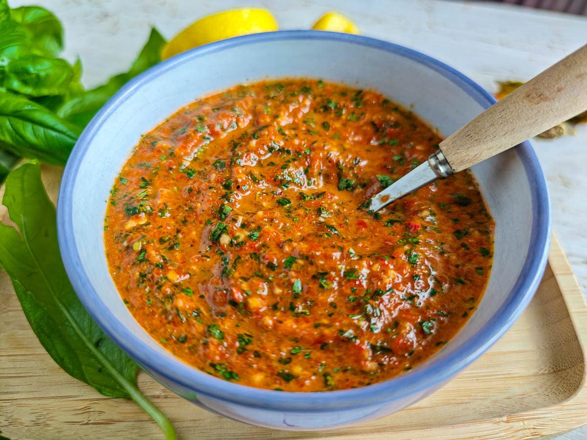 Easy Red Chimichurri Sauce with Roasted Peppers Roasted pepper chimichurri in a bowl with a spoon in it.